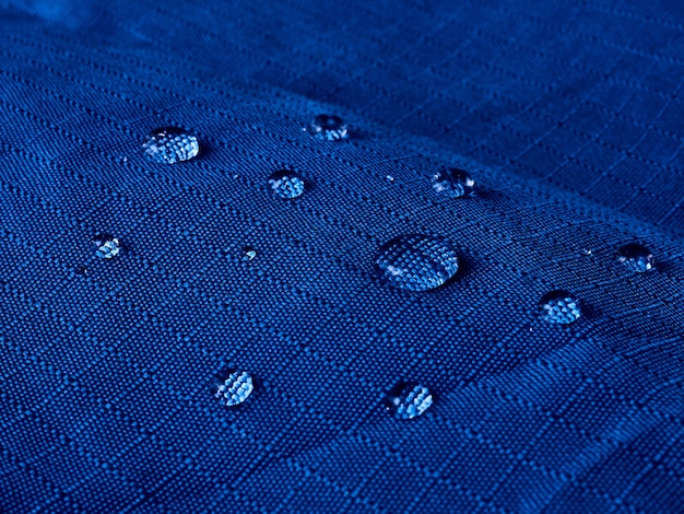 Waterdruppels op waterdichte membraanstof. Detailweergave van textuur van blauwe waterdichte doek.