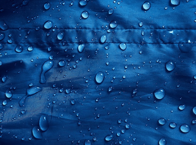 Waterdruppels op waterdichte membraanstof. Detailweergave van textuur van blauwe waterdichte doek.