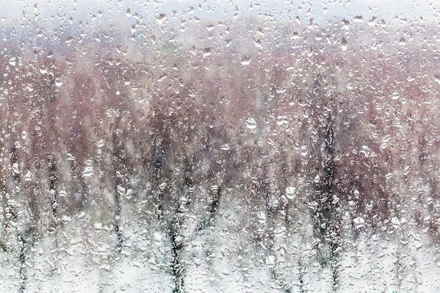 Waterdruppels van smeltende sneeuw op vensterglas in huis
