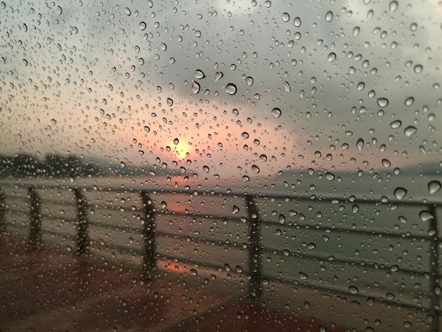 Foto waterdruppeltjes op een glazen venster in de zonsondergang.