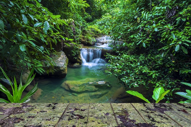 Waterfall background with wooden balcony covered by lichen.