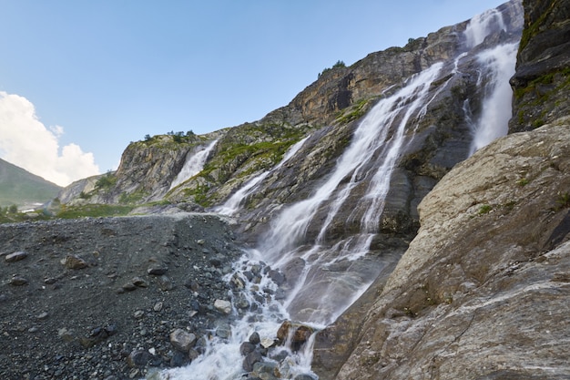 Waterfall in the Caucasus mountains, melting glacier ridge Arkhyz, Sofia waterfalls. Beautiful high mountains of Russia, the river of pure ice water. Summer in the mountains, hike