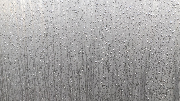 車の塗装ガラスの水滴が灰色の色合いで落ちる滝の効果