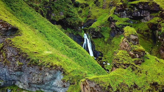 Photo a waterfall in a green valley with mossy rocks and a waterfall