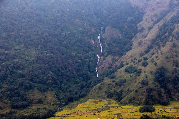 A waterfall is on the side of a hill in the distance