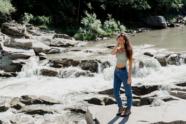 Waterfall in mountain river. Girl travelling in Karpathian mountains and feeling freedom.