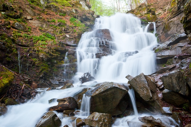 Водопад льется со скалы на камни