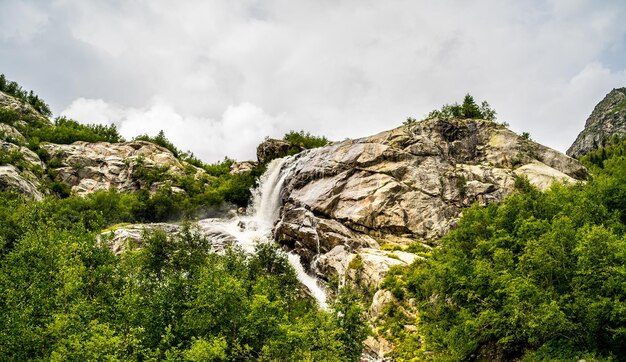 Waterfall on summer day in nature Rapid water stream falling from rocks against blue sky on sunny summer day in countryside