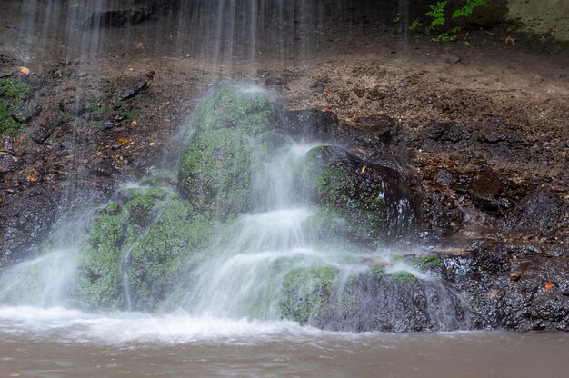 Waterfall on wet black and green stones