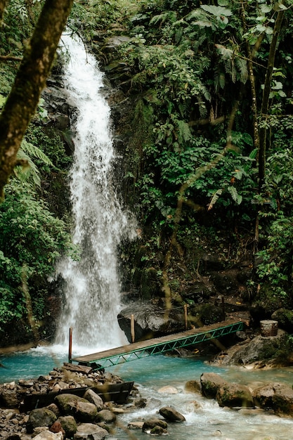 Waterfall with a wood bridge in the middle of the forest in Alajuela, Costa Rica.