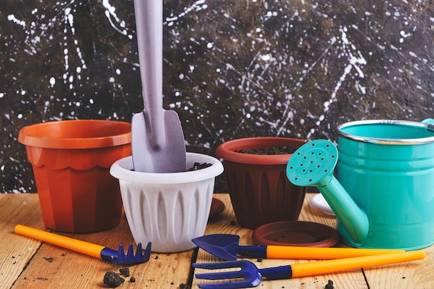 Watering can flower pots and gardening tools on a wooden table