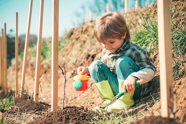 Watering flowers in garden little farmer with shovel and watering can moments in the countryside chi