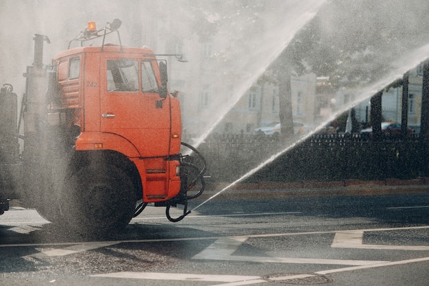 Поливочная машина наливает воду на дорогу