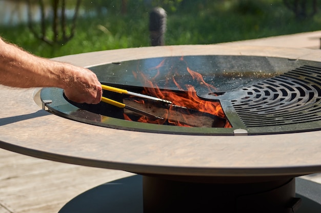 Waterkoker grill pit met gietijzeren rooster met vlammen ronde tafel kookoppervlak hete bbq op achtertuin