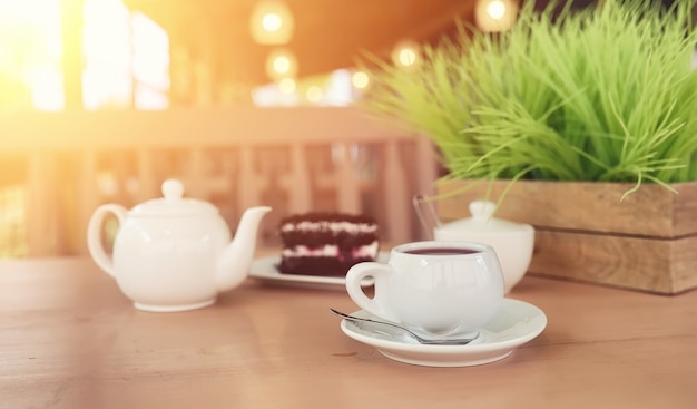 Waterkoker met een drankje en dessert in straatcafé. Thee in de waterkoker beker op tafel. Ontbijt met thee en gebak in het café.