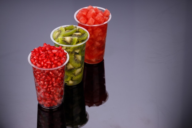 Watermeloen, granaatappel en Kiwi Slices gerangschikt in twee transparante glazen met witte achtergrond, geïsoleerd