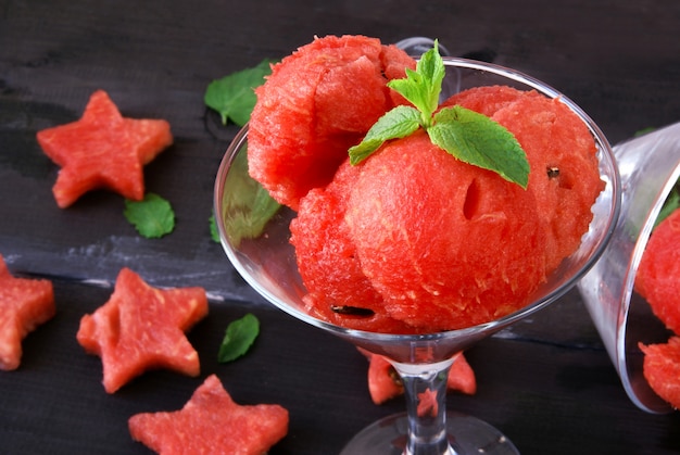 Watermeloen met een lepel voor het snijden van cocktailballen, een glas met balletjes watermeloen