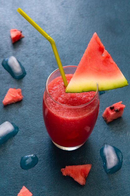 Watermeloen smoothie en stukjes ijs op een blauwe tafel