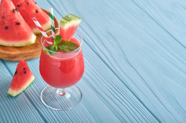 Watermeloencocktail met munt en ijs. Zomer verfrissende drankjes in glazen op blauwe houten tafel. Concept van gezond zomer eten.