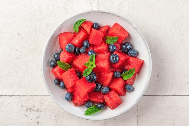 Watermeloensalade met bosbessen en munt in een bord op witte tafel bovenaanzicht gezond zomerdessert