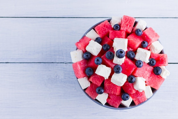 Watermeloensalade met feta kaas in een grijze kom Gezonde salade met bosbessen watermeloen