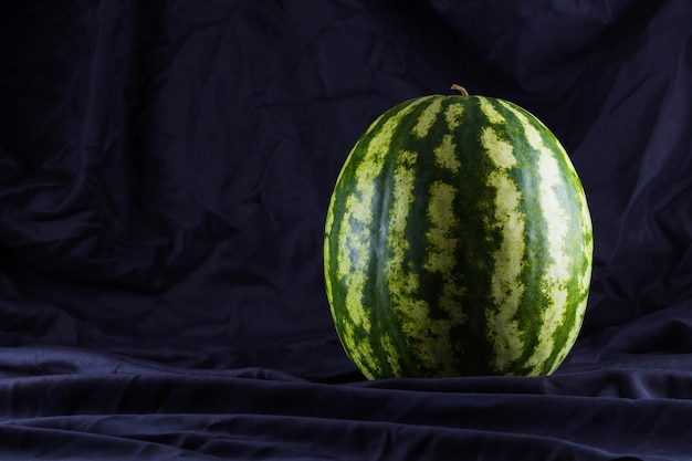 Watermelon on black cloth Whole watermelon on dark background Healthy food for vegan Copy space