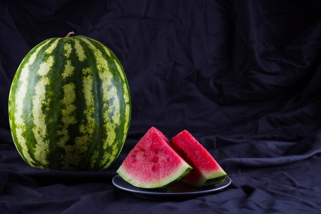 Watermelon on black cloth Whole watermelon on dark background Healthy food for vegan Copy space