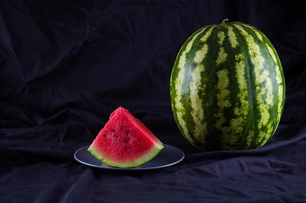 Watermelon on black cloth Whole watermelon on dark background Healthy food for vegan Copy space