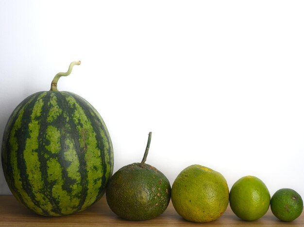 Watermelon and citrus fruits on a wooden table against white background