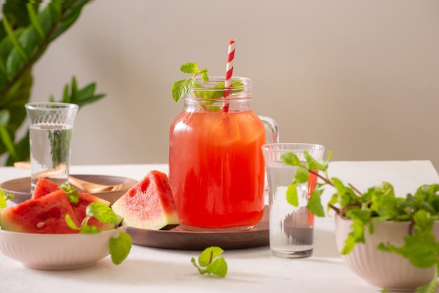 Watermelon drink in glass with slices of watermelon on whitesurface