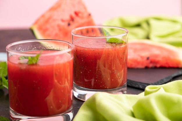 Watermelon juice with chia seeds and mint in glass on a black concrete background with green textile. Healthy drink concept. Side view,  close up, selective focus.