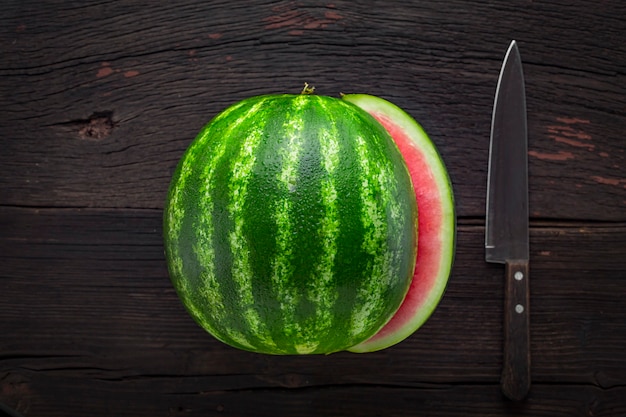 watermelon and knife on wooden table