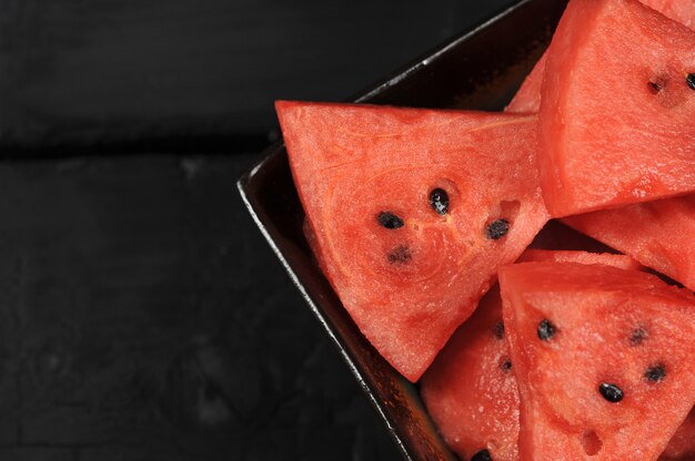 Photo watermelon pieces in a black bowl