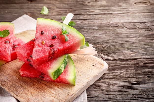 Photo watermelon pieces on sticks on wooden background. copy space.