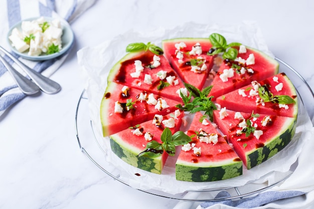 Watermelon pizza with feta cheese and herbs on a table