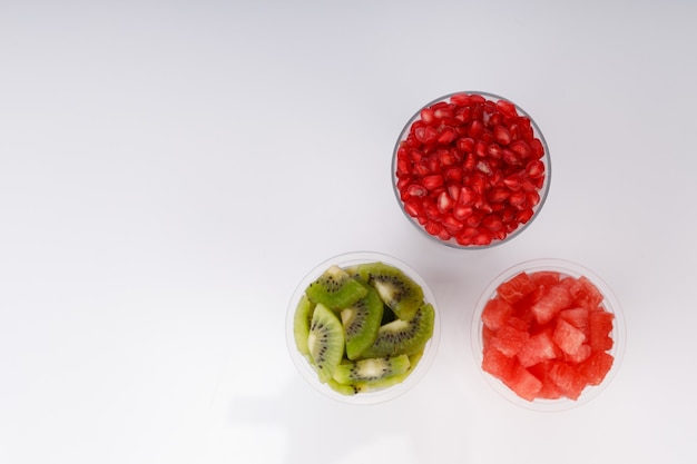 Watermelon , pomogrenate and Kiwi Slices arranged  in two transparent glasses with white background, isolated