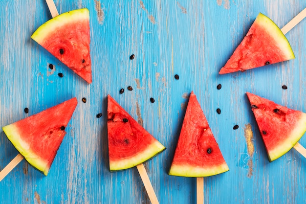 Watermelon popsicles over blue wooden background