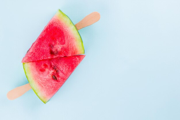 Watermelon slice popsicles on a turquoise background Fresh watermelon on wooden sticks