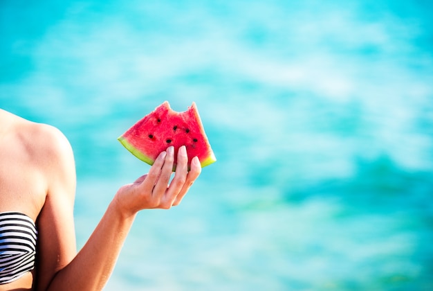 Watermelon slice in woman hand over sea
