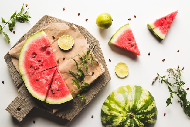 Photo watermelon on a sliced board with mint and slices of lime. food