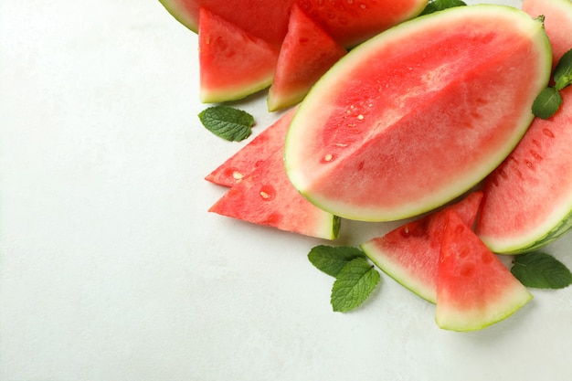 Watermelon slices and mint leaves on white textured table