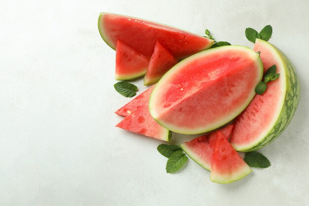 Watermelon slices and mint leaves on white textured table