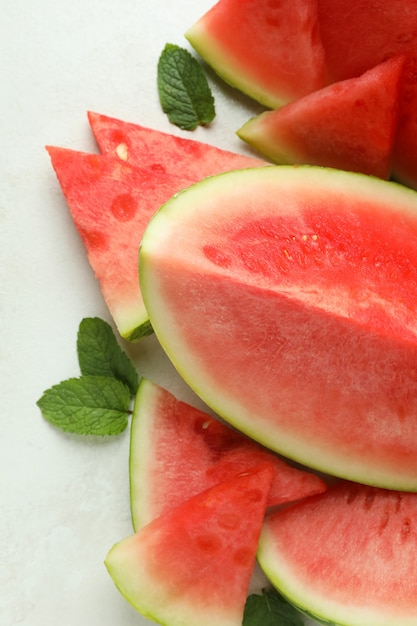 Watermelon slices and mint leaves on white textured table