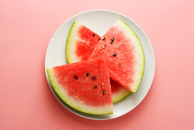 Watermelon slices in plate isolated on pink background 