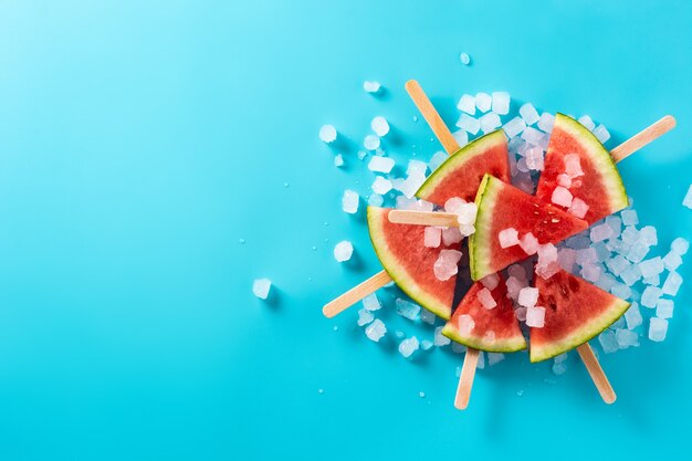 Watermelon slices popsicles on blue surface