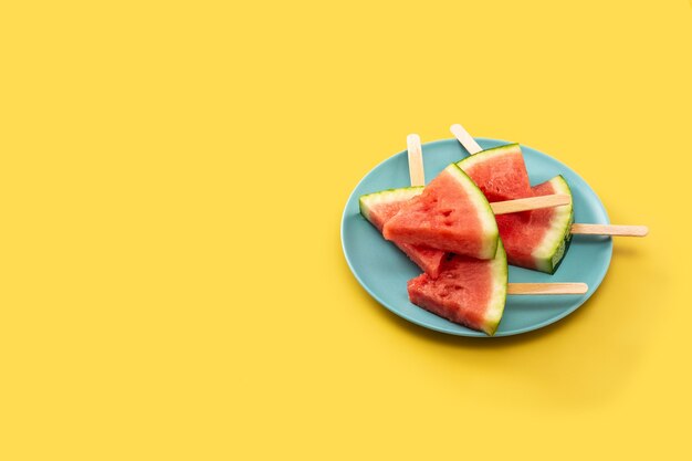 Watermelon slices popsicles on yellow