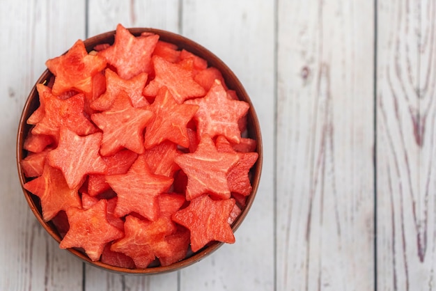 Watermelon slices in the shape of a star in bowl on a light wood. Top view,