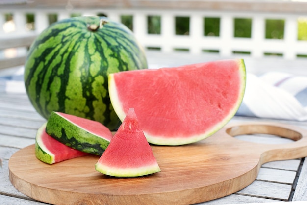 Watermelon and slices on a table on wooden terrace