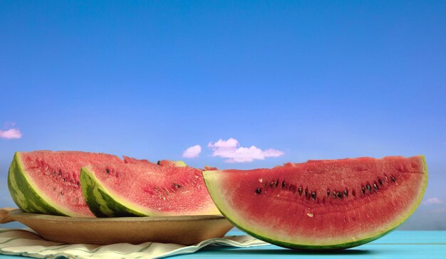 Watermelon slices on a wooden table blue sky background