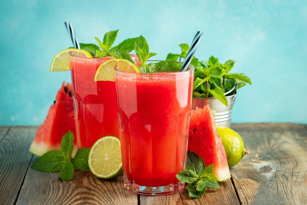 Watermelon slushie with lime and mint summer refreshing drink in tall glasses on a light blue background Sweet cold smoothie